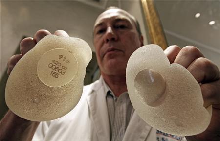Plastic surgeon Denis Boucq poses with silicone gel breast implants manufactured by French company Poly Implant Prothese (PIP) in a clinic in Nice