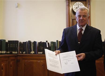 Hungary's President Pal Schmitt holds an official copy of Hungary's new constitution at the National Archives of Hungary in Budapest January 5, 2012. REUTERS/Laszlo Balogh