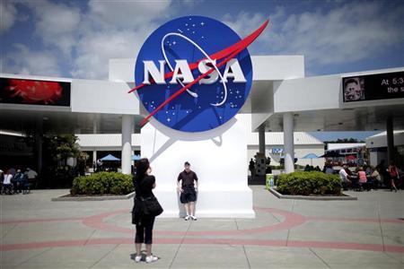 Tourists take pictures of a NASA sign at the Kennedy Space Center visitors complex in Cape Canaveral,