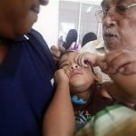 Kadir is comforted by his grandfather Mamat after being circumcised during a mass circumcision ceremony in Sungai Pelek, outside Kuala Lumpur
