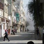 People run for cover from smoke after a shelling in the Karm al-Zeitoun area in Homs