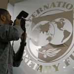 A photographer takes pictures through a glass carrying the International Monetary Fund (IMF) logo during a news conference in Bucharest March 25, 2009. REUTERS/Bogdan Cristel