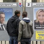 People stop to read the official campaign posters for candidates in the French presidential election: Nicolas Sarkozy, France's President and UMP candidate and Marine Le Pen, France's National Front head in Paris, April 9, 2012. REUTERS/Benoit Tessier