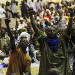 Malians, who originate from the north, pump their fists in the air during a meeting at the Palace of Congress in Bamako April 4, 2012. REUTERS/Luc Gnago