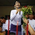 Myanmar's pro-democracy leader Aung San Suu Kyi receives flowers as she addresses supporters and reporters from behind the gates of the National League for Democracy (NLD) office in Yangon April 2, 2012. REUTERS/staff