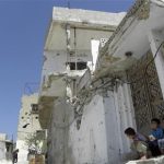 Syrian children sit in front of their damaged house in Talbisa area in Homs, northern Syria April 10, 2012. REUTERS/Stringer