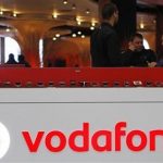 The Vodafone logo is seen at the counter of the shop as customers look at mobile phones in Prague February 7, 2012. REUTERS/David W Cerny