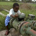 A child plays with a pipe near an oil well in Olomoro village in Isoko, a local government area of Delta region in Nigeria, March 28, 2007. REUTERS/George Esiri