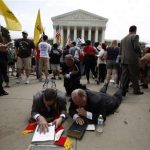 Religious leaders lay on the ground and pray over a bible and a copy of the verdict on President Barack Obama's signature healthcare overhaul law outside the Supreme Court in Washington June 28, 2012. REUTERS/Jason Reed