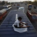 The helper of a driver rests on top of his parked truck along a busy highway on the outskirts of New Delhi June 15, 2012. Picture taken June 15, 2012. REUTERS/Adnan Abidi