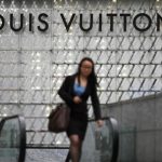 A woman walks by a Louis Vuitton luxury boutique at the IFC Mall in Shanghai June 4, 2012. REUTERS/Carlos Barria