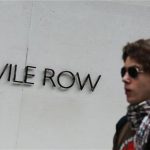 A man passes a Savile Row sign, in London August 21, 2010. REUTERS/Luke MacGregor