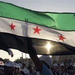 People shout slogans in support of Colonel Hassan Hamada, a Syrian air force pilot who flew his MiG-21 fighter plane over the border to Jordan on Thursday, and wave a Syrian opposition flag during a demonstration against Syria's President Bashar al-Assad outside the Syrian embassy in Amman June 21, 2012. REUTERS/Ali Jarekji