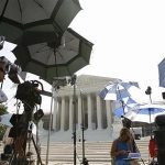 TV camera crew protect themselves from the sun during a stakeout at the U.S. Supreme Court in Washington June 21, 2012. REUTERS/Jose Luis Magana