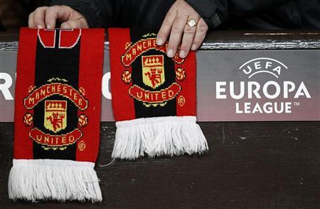 A Manchester United supporter adjusts a club scarf before their Europa League second leg round of 32 soccer match against Ajax at Old Trafford in Manchester, northern England, February 23, 2012. REUTERS/Phil Noble