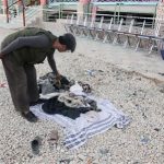 A man searches clothes of victims at the site of attack in Samangan province July 14, 2012. REUTERS/Stringer
