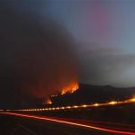 A forest fire is seen on a hill as a fire engine speeds past in the Vilaflor municipality, on the southern part of Spanish Canary Islands of Tenerife, July 18, 2012. REUTERS/Santiago Ferrero