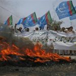 Supporters of Islami Jamiat Talaba, a student wing of Pakistan religious and political party Jamaat-e-Islami, hold their party flags as they burn tyres on the road during an anti-American demonstration in Peshawar, July 5, 2012. REUTERS/Khuram Parvez