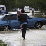 A local resident walks with her child through a flooded street in the southern Russian town of Krymsk July 7, 2012. At least 99 people were killed in floods and landslides in southern Russia after two months' average rainfall fell in a few hours overnight, police and emergency officials said on Saturday. REUTERS/Vladimir Anosov
