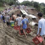 People carry their merchandise on a muddy part of the collapsed road in suburban Antipolo City, east of Manila, on Thursday.