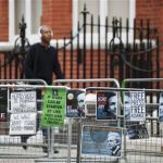 A man walks past a barrier with Free Julian Assange posters opposite the Ecuadorean Embassy in London August 14, 2012. REUTERS/Ki Price