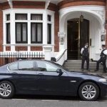 Police officers stand on the steps of Ecuador's embassy as an Ecuadorean diplomatic car is seen parked outside in London August 15, 2012. REUTERS/Neil Hall