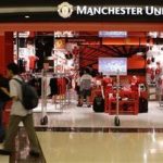 Shoppers walk past a Manchester United merchandise store at a mall in Singapore June 14, 2012. REUTERS/Tim Chong