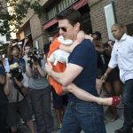 Actor Tom Cruise carries his daughter Suri past a group of photographers as they make their way from a hotel in New York, July 17, 2012. REUTERS/Keith Bedford