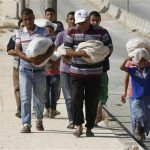 Civilians carry bread along a street in the city of Aleppo August 28, 2012. REUTERS/Youssef Boudlal