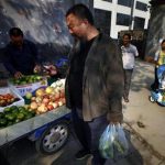 Dissident Chinese artist Ai Weiwei (C) buys fruit from a local vendor on the street outside the Chaoyang District Court before trying to attend his appeal verdict hearing in Beijing September 27, 2012. REUTERS/David Gray