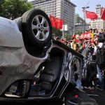 Demonstrators hold Chinese flags and banners beside an overturned car of a Japanese brand during a protest in Xi'an, Shaanxi province September 15, 2012. REUTERS/Rooney Chen