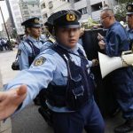 A policeman gestures at a photographer to stop taking pictures as he and other police officers block a protester shouting anti-China slogans in front of the Chinese Embassy in Tokyo September 28, 2012. REUTERS/Kim Kyung-Hoon