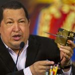 Venezuela's President Hugo Chavez talks to the media as he holds a model of the new Miranda Satellite in Caracas February 10, 2012. REUTERS/Carlos Garcia Rawlins