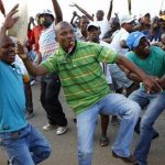 Striking miners dance and cheer after they were informed of a 22 percent wage increase offer outside Lonmin's Marikana mine, 100 km (60 miles) northwest of Johannesburg, September 18, 2012. REUTERS/Siphiwe Sibeko