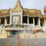 A mourner burns incense sticks as people gather to wait for the arrival of the remains of the late former Cambodian King Norodom Sihanouk at the Royal Palace in Phnom Penh early October 17, 2012. REUTERS/Damir Sagolj