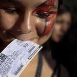 A Lady Gaga fan holds her VIP ticket in her mouth as she stands outside the venue where the U.S. pop star will perform a concert, in Buenos Aires, Argentina, Friday, Nov. 16, 2012. The Latin American leg of her, "Born This Way Ball Tour," is coming to an end but not before stopping in Chile, Peru and Paraguay. (AP Photo/Natacha Pisarenko)