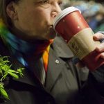 Wearing items representative of the state's historic events, Desiree Moore, a 20-year marijuana activist, takes a sip of her coffee at a marijuana smoke out event in Seattle, Washington December 6, 2012. Hundreds of marijuana enthusiasts huddled near Seattle's famed Space Needle tower on Thursday night with pipes, bongs and hand-rolled joints to celebrate Washington's new status as the first state in the nation to legalize pot for adult recreational use. REUTERS/Jordan Stead
