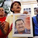 A supporter of Venezuelan President Hugo Chavez holds a picture of him, as she attends a ceremony to pray for his health in Caracas December 20, 2012. REUTERS/Carlos Garcia Rawlins