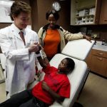 WEST HILLS, CA - DECEMBER 26, 2012: Dr. Peter H. Grossman, left, shacks hands with Adolf Baguma, 11, of Uganda, while Adolf's guardian Eva Mbabazi, 32, looks on in Dr. Grossman's office in West Hills, CA December 26, 2012. At the age of 5, Adolf was burned by a relative seeking to punish him for taking food. He was left without the ability to walk upright as the skin on the back of his legs fused together. He was abandoned and left in the streets. A Los Angeles attorney met Adolf while on a mission to Uganda. He worked with the Children's Burn Foundation, and Adolf was brought to the Grossman Burn Center, where he underwent a series of corrective surgical procedures to allow him to walk again. (Francine Orr / Los Angeles Times)
