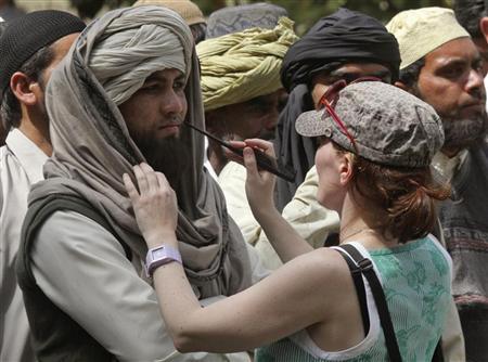 A crew member of Oscar-winning director Kathryn Bigelow's team for the movie "Zero Dark Thirty" applies makeup on an actor during a shoot at the filming location in the northern Indian city of Chandigarh March 17, 2012. REUTERS/Ajay Verma