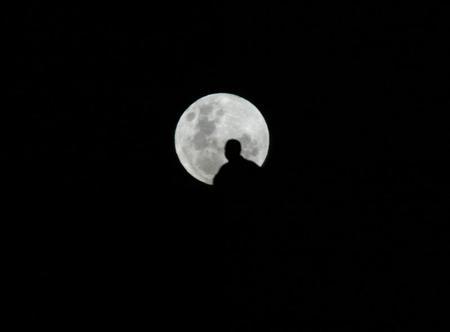 MAN LOOKS AT FULL MOON IN SYDNEY. A man looks at the full moon atop a hill in Sydney June 14, 2003. REUTERS/David Gray