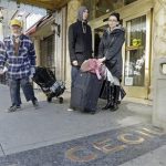 A man, left, leaves the Cecil Hotel with belongings as Michael and Sabina Baugh, both 27, of Plymouth, England, wait for transportation as they leave the hotel in downtown Los Angeles Wednesday, Feb. 20, 2013. Early Tuesday, police discovered the body of a Canadian woman at the bottom of the historic hotel's water tank, weeks after she was reported missing. The Baughs, on a 14-day tour package, had been there eight days and had showered in and drank the water. The couple's tour operator was less than cooperative in finding them other accommodations. (AP Photo/Reed Saxon)