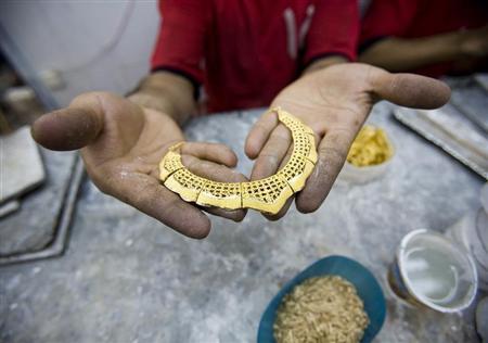 A worker holds a gold necklace at a gold workshop in the city of Isfahan, 414 km (259 miles) south of Tehran May 3, 2007. REUTERS/Morteza Nikoubazl