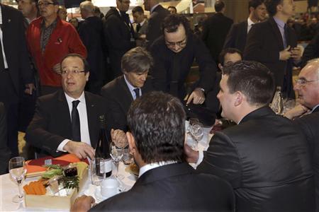 French President Francois Hollande (L) shares a breakfast with farmers during his visit at the 50th International Agricultural Show in Paris, February 23, 2013. The Paris Farm Show runs from February 23 to March 3, 2013. REUTERS/Philippe Wojazer