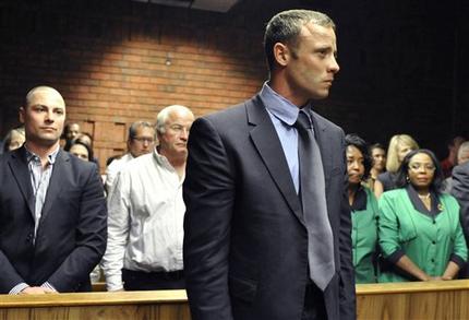 Olympian Oscar Pistorius, foreground, stands following his bail hearing, as his brother Carl, left, and father Henke, second from left, look on in Pretoria, South Africa, Tuesday, Feb. 19, 2013. Pistorius fired into the door of a small bathroom where his girlfriend was cowering after a shouting match on Valentine's Day, hitting her three times, a South African prosecutor said Tuesday as he charged the sports icon with premeditated murder. The magistrate ruled that Pistorius faces the harshest bail requirements available in South African law. He did not elaborate before a break was called in the session. (AP Photo)