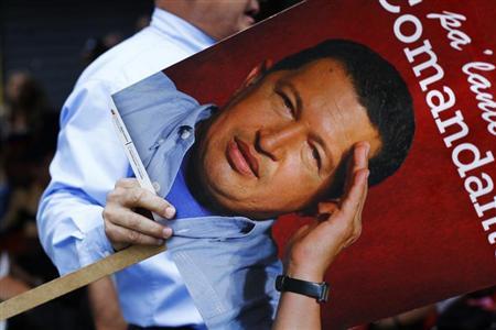 A supporter of Venezuelan President Hugo Chavez holds a picture of him as he takes part in a gathering at Plaza Bolivar in Caracas February 18, 2013. Chavez made a surprise return from Cuba on Monday more than two months after surgery for cancer that has jeopardized his 14-year rule of the South American OPEC member. The 58-year-old socialist leader underwent a six-hour operation in Cuba on December 11. He had not been seen or heard in public since then until photos were published of him on Friday. REUTERS/Carlos Garcia Rawlins