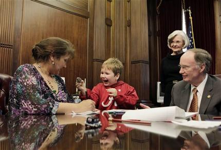 In this photo provided by the Governor's office, from right to left, Alabama Gov. Robert Bentley and First Lady Dianne Bentley watch as Ethan Gilman shows his mother, Jennifer Kirkland, a toy mouse Bentley gave him to play with on a visit to the Governor's Office in Montgomery, Ala. on Wednesday, Feb. 13, 2012. Ethan was held hostage in an underground bunker in a near week-long standoff in Midland City, Ala. (AP Photo/Alabama Governor's Office, Jamie Martin)