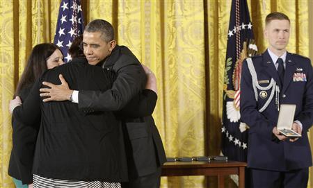U.S. President Barack Obama (3rd L) hugs Sarah Davino (L) and Mary Davino (2nd L), as he awards the Presidential Citizens Medal posthumously to their family member Rachel Davino, a teacher who gave her life in the Sandy Hook school shooting in Connecticut in December, in the East Room at the White House in Washington, February 15, 2013. REUTERS/Jonathan Ernst