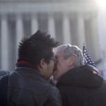 Wyatt Tan, left and Mark Nomadiou, both of New York City, kiss in front of the Supreme Court in Washington, Wednesday, March 27, 2013, prior to the start of a court hearing on the 1996 Defense of Marriage Act (DOMA). In the second of back-to-back gay marriage cases, the Supreme Court is turning to a constitutional challenge to the law that prevents legally married gay Americans from collecting federal benefits generally available to straight married couples. (AP Photo/Carolyn Kaster)