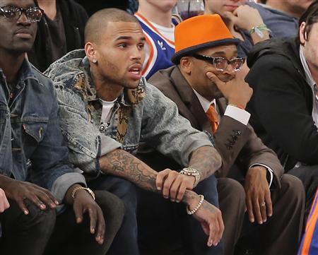Entertainer Chris Brown watches next to film director Spike Lee (R) as the New York Knicks play the Boston Celtics in the third quarter of their NBA basketball game at Madison Square Garden in New York, March 31, 2013. REUTERS/Ray Stubblebine